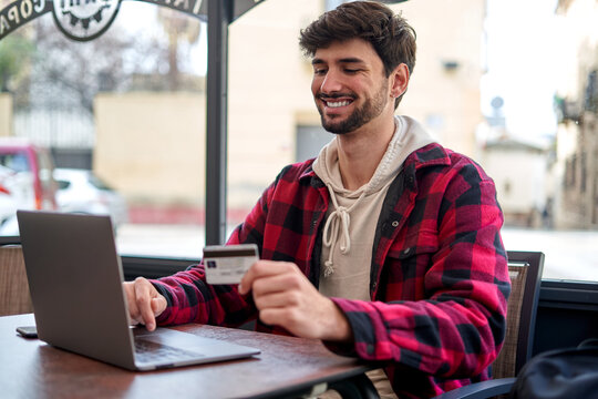 Cheerful man making online payment via laptop