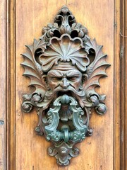 Dekorativer, reich verzierter Türöffner an einer historischen Holztür in Florenz, Italien