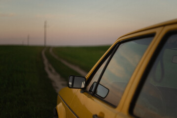 Yellow retro car on the countryside road at sunset. 