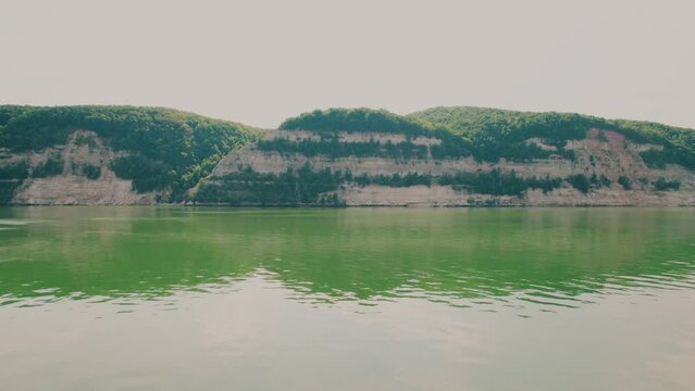 Shot on a drone. The border of water and land. Hills. A small hill.  Rocky steep river bank. Beautiful landscape.