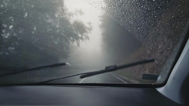 Handheld cinematic shot from the car's cabin. Driving in the rain on a winding mountain road.