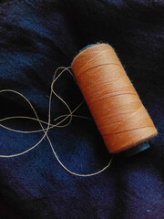 spools of thread, yellow thread on black cloth, sewing tool