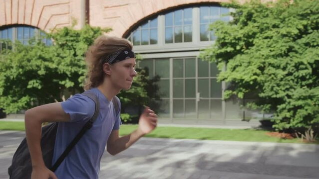 Side view of teenage boy with back pack running to school being late