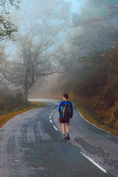 Tourist with backpack walking up on hill