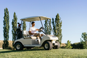 Athlete driving golf cart in green field