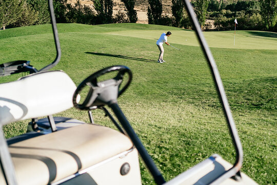 Unrecognizable golfer playing golf on course in sunlight