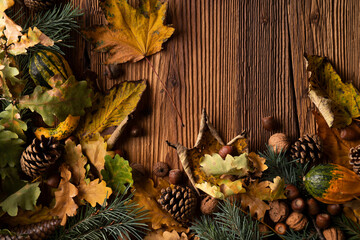 Fototapeta na wymiar Autumn composition on a rustic wooden background. Decorative pumpkins, various leaves, pine cones, nuts. Orange, yellow, red and brown aesthetics. 