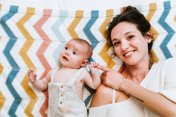 Happy mother with cute baby chilling on bed at home