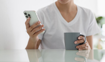 Fototapeta premium Close-up shot of young woman using smartphone at home, working holiday.