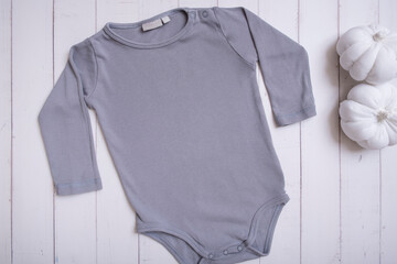 Grey baby bodysuit mockup for logo, text or design on wooden background with pumpkins top view