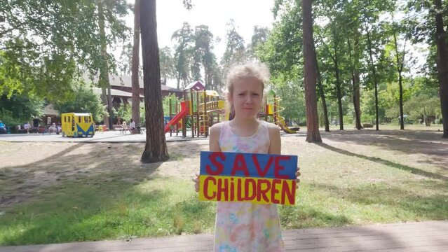Ukrainian girl in her hands holds a poster with the inscription save the children. She asks for help to save from the war.