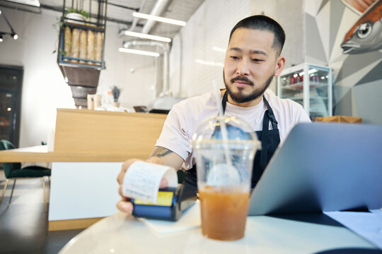 Professional coffee shop worker making a copy of a payment receipt