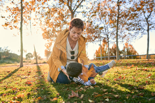 Happy LGTB couple tickling little son in park in fall
