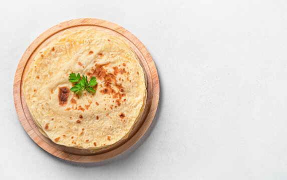 Chapati, traditional Indian flatbreads with fresh parsley on a gray background. Top view, horizontal