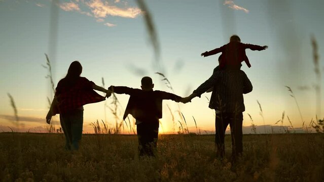 Big family, group of people, nature. Active family with children walks in grass field in summer. Silhouette family, Dad mom daughter son go hand in hand outdoors in autumn. Parental care for children