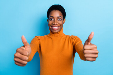 Photo of cheerful nice promoter unisex person show thumb up wear yellow turtleneck isolated blue color background