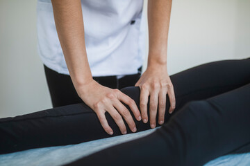 Anonymous therapist massaging leg of patient