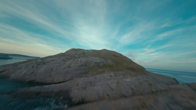 Mumbles Lighthouse 4K FPV Drone Footage Aerial View over the ocean looking back to the mainland with Mumbles Pier to the side during summer time at Mumbles, Swansea, South Wales, United Kingdom