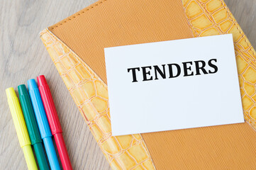 TENDER text on a card that sits on a yellow notebook on a wooden table