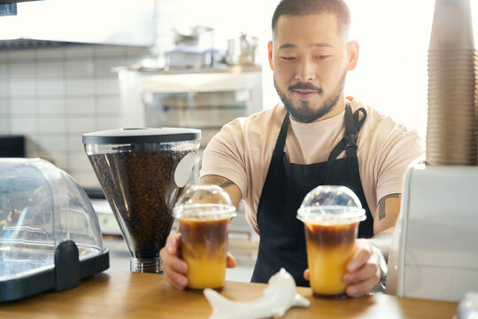 Lovely Asian Coffee Shop Worker Presenting Two Fresh Iced Beverages