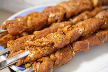 Marinated meat for kebab on skewers lies on a plate