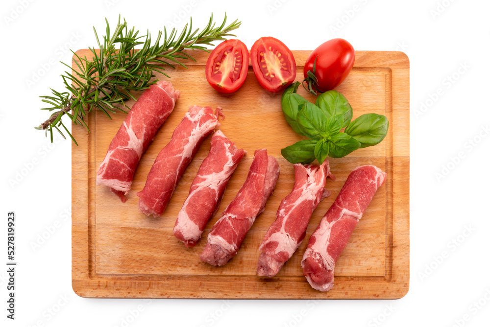 Wall mural raw pork neck steak rolls (coppa) on wooden cutting board with rosemary, chopped cherry tomatoes and