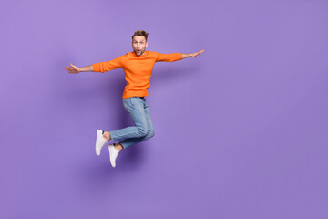 Fototapeta na wymiar Full length photo of ecstatic delighted man jumping up have fun during summer vacation isolated on violet color background