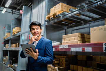 Concept of supply chain. Asian businessman checking inventory items at a logistics warehouse on goods. Import-export transportation business. happy workers in distribution .