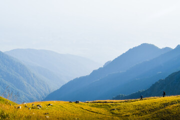 Two male friends hikers in distance hike on trail outdoors on beautiful sunset in autumn together. Active people on trek in caucasus mountains