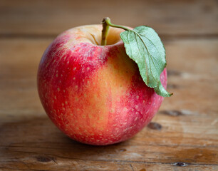 freshly picked red apple with green leaf on rustic wooden table
