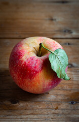 freshly picked red apple with green leaf on rustic wooden table