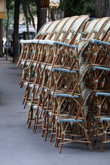 Fototapeta na wymiar Paris, France - 08.07.2022: Restaurant terrace chairs stacked on top of each other and waiting for the opening of the restaurant