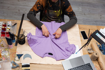 Cropped view of african american craftswoman working with t-shirt in workshop.