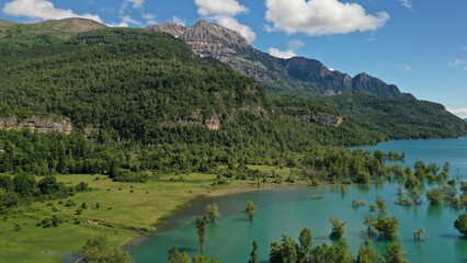 Wild horses in the green field near the blue lake in Pyrenees mountains in Arragon, Spain.