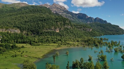 Naklejka na ściany i meble Wild horses in the green field near the blue lake in Pyrenees mountains in Arragon, Spain.