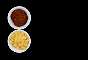 Yellow mustard and red Chilli powder in White bowls on a black background
