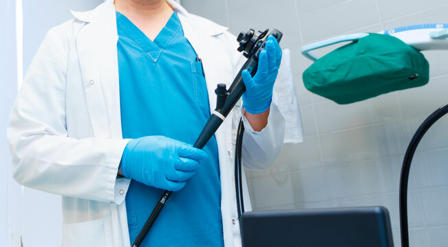 Selective focus on doctor's hands holding an endoscope. Doctor's hands in sterile gloves hold an endoscope for colonoscopy and early detection of cancerous tumors in the intestine.