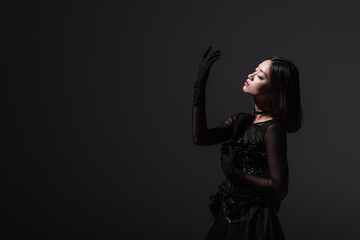 sensual asian woman in gothic dress gesturing isolated on grey.