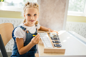 Portrait of blond girl practice with xylophone in the school of music. Looking at camera.