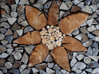 Eine in einem Holzstapel eingearbeitete, stilisierte Edelweißblüte aus Holz