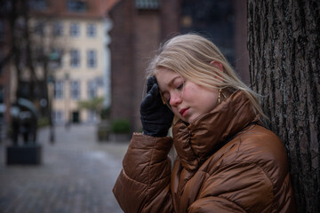 Sad girl with hands on forehead and look down, mental health concept, copy space on the left.