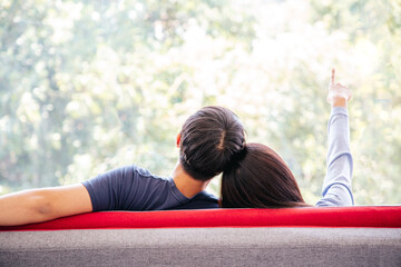 Back view of Lovely Couple sitting and feeling relax on red sofa with Green Outdoor Park View....