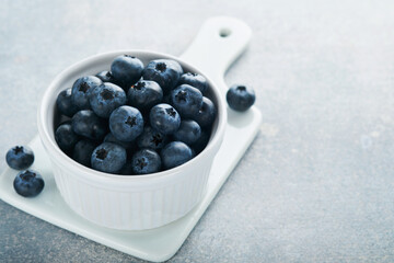 Blueberry. White bowl of fresh blueberries on grey stone background table. Tasty ripe blueberries. Place for text. Food background. Top view.