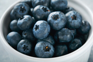 Blueberry. White bowl of fresh blueberries on grey stone background table. Tasty ripe blueberries. Place for text. Food background. Top view.