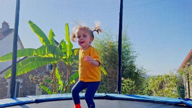 Beautiful little girl jump on trampoline, hot summer day