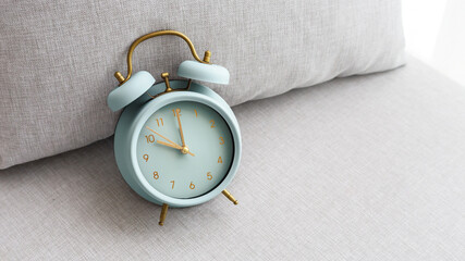 Pastel blue vintage alarm clock on fabric couch background