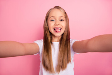 Photo of excited carefree girl make selfie showing tongue out isolated on pink color background