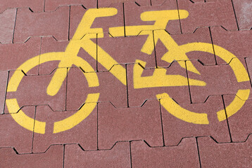 Yellow bicycle sign on the paving stone road