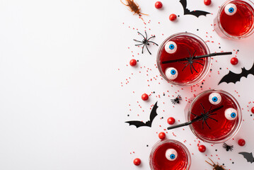 Halloween party concept. Top view photo of floating eyes punch in glasses red candies bat...
