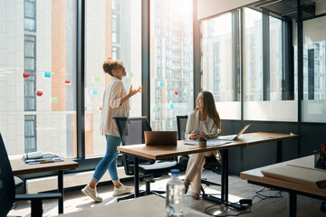 Joyful women employees talking while working in spacious office